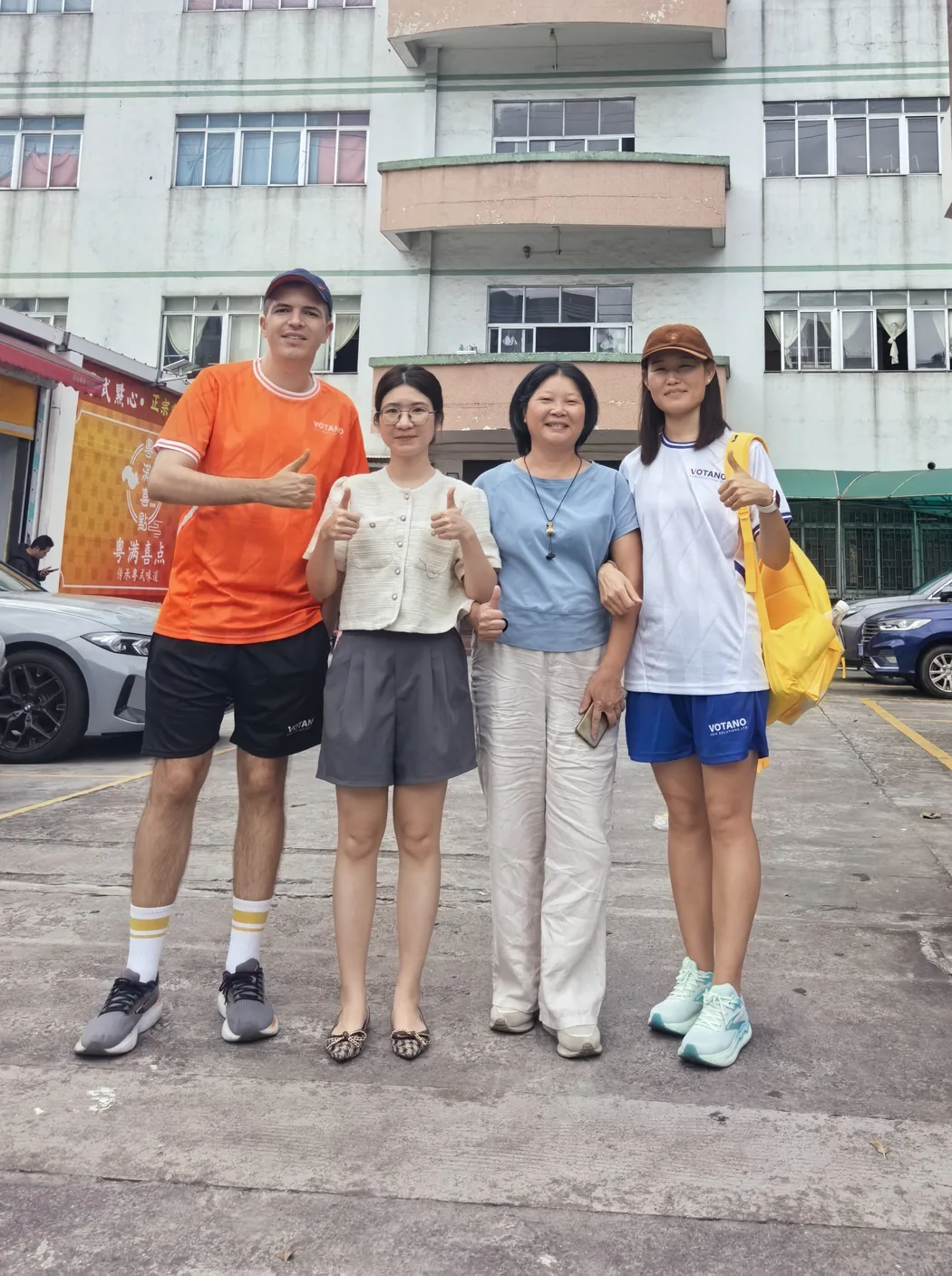 Luciano Votano et Bai Rongli avec des partenaires de l'usine devant une usine de confection à Foshan