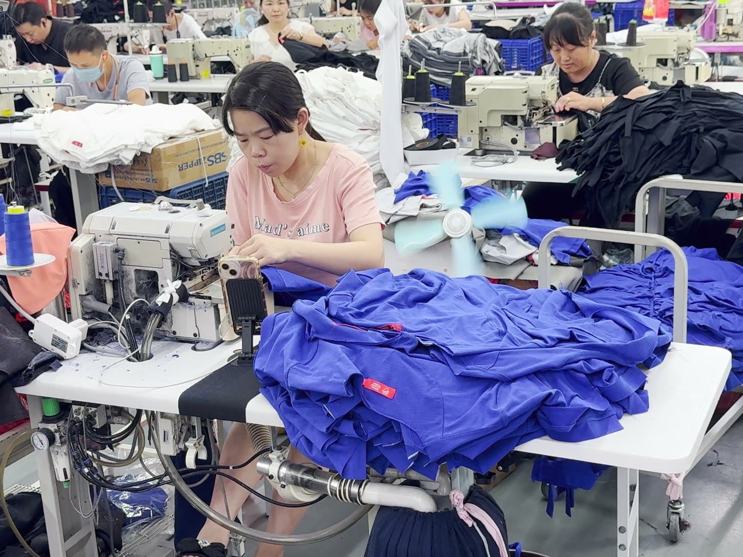 Des opératrices assemblent des maillots sur une ligne de production dans une usine textile chinoise