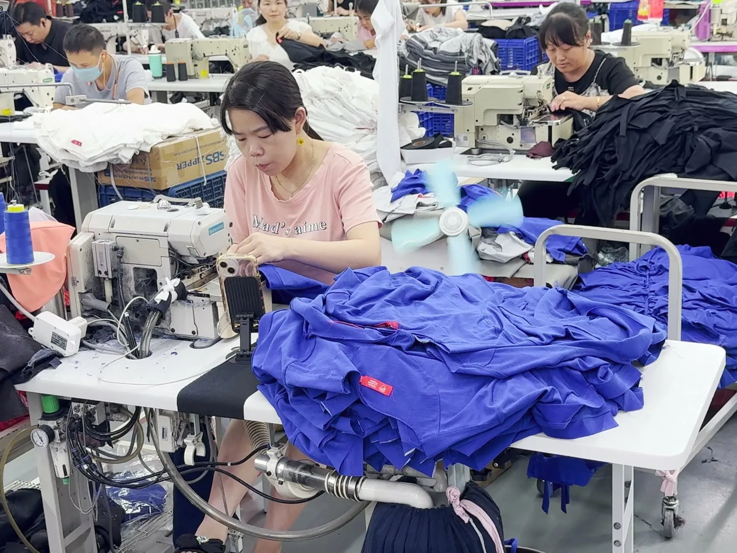Des opératrices assemblent des maillots sur une ligne de production dans une usine textile chinoise